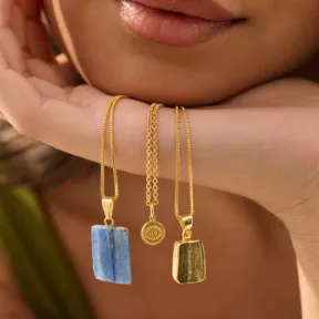 Gold necklaces and gemstone pendants draped across a hand