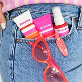Nexscope beauty products and coral sunglasses in a denim pocket